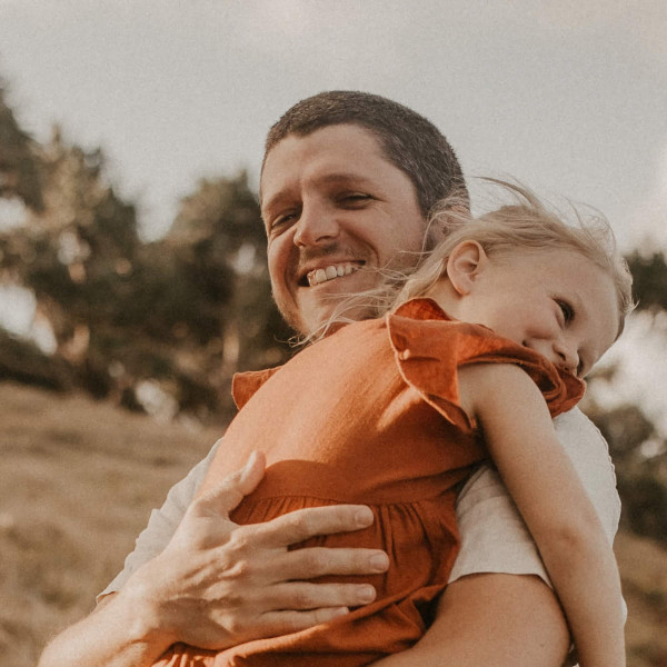 Brad smiling and hugging his daughter Evergrace.