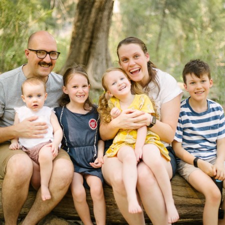 Lauren & Jeremy sitting outside and smiling with their four children.