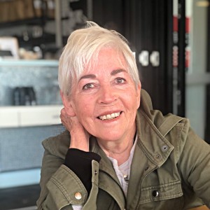 Nana Deidre smiling at a cafe, wearing a green jacket.