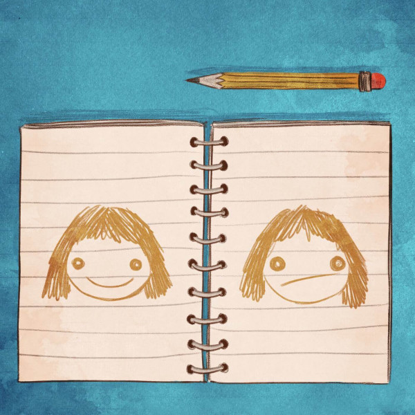 A journal and pencil on a desk, with a happy face and a sad face